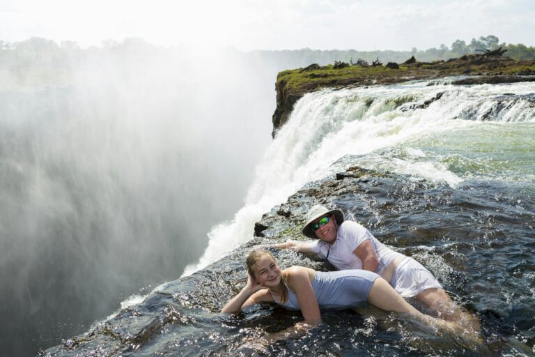 Man and a girl in the water of the Devil's Pool on the edge of Victoria Falls.